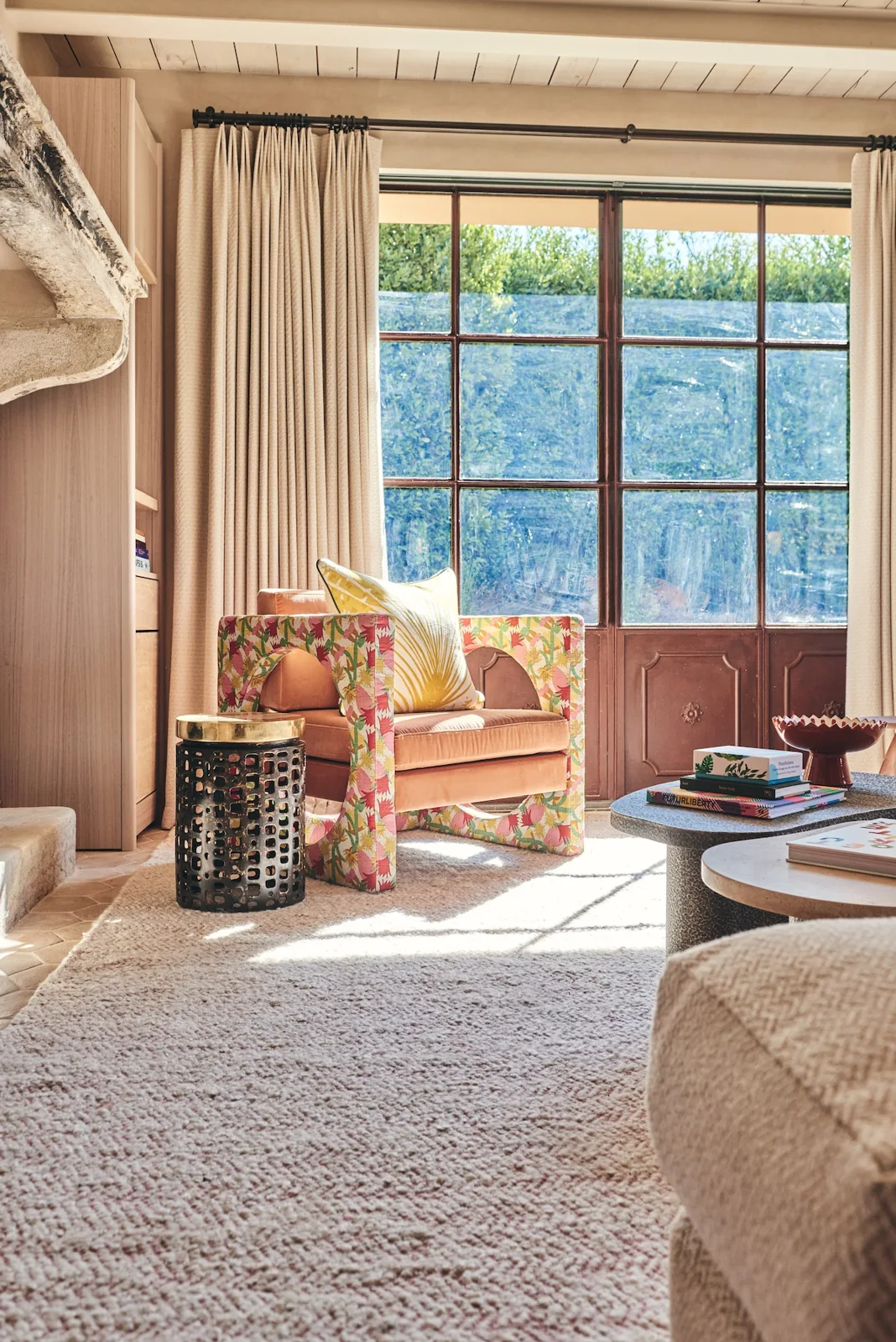 Sunlit sitting room with a floral armchair and tall glazed doors