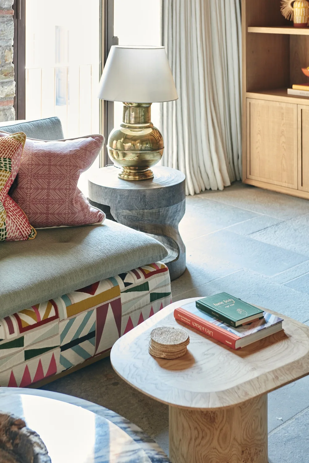 Colourful textiles, a sculptural side table and pale timber joinery