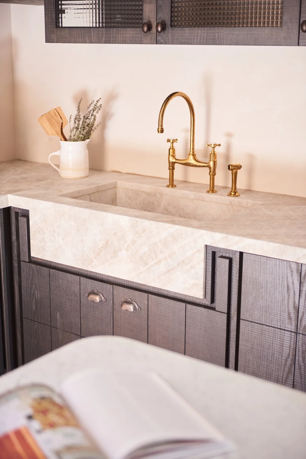 Stone sink and brass tap with dark cabinetry